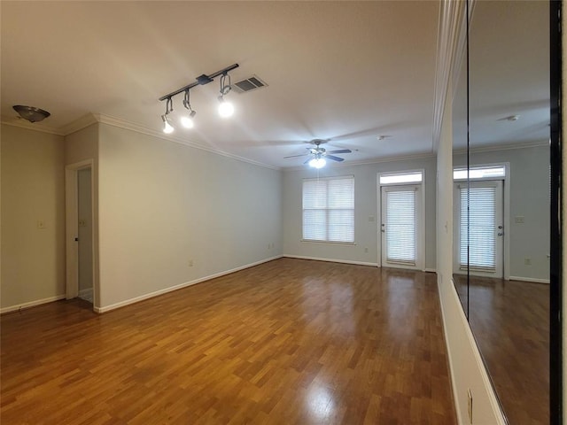 empty room featuring ceiling fan, crown molding, visible vents, and wood finished floors