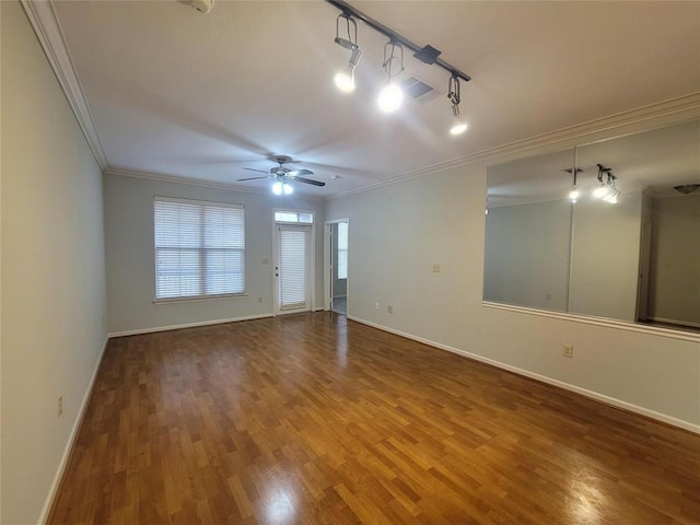 empty room with ceiling fan, crown molding, wood finished floors, baseboards, and track lighting