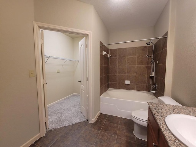 bathroom with toilet, tile patterned floors, a walk in closet, vanity, and washtub / shower combination