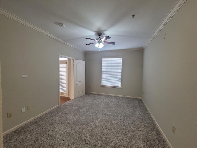 carpeted spare room with baseboards, ceiling fan, and crown molding