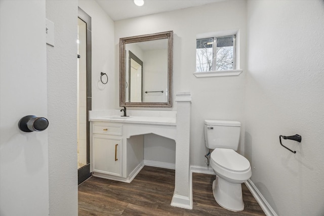 bathroom with toilet, baseboards, wood finished floors, and vanity