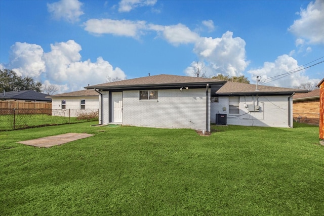 back of property with a lawn, roof with shingles, fence, cooling unit, and brick siding