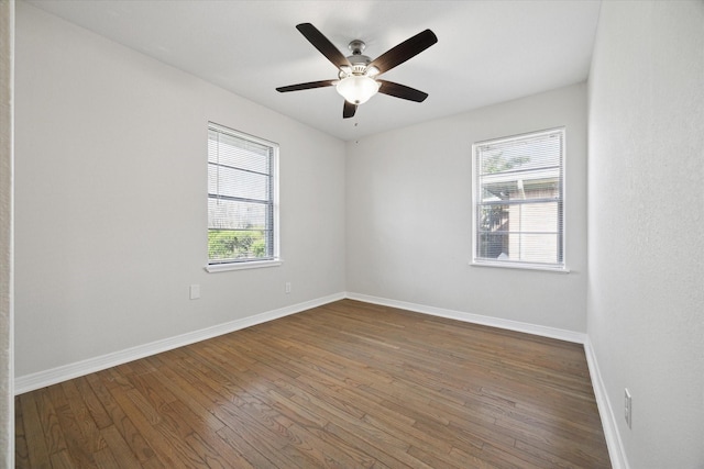 spare room featuring a ceiling fan, baseboards, and dark wood-style flooring