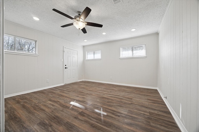 unfurnished room with visible vents, baseboards, a ceiling fan, dark wood finished floors, and a textured ceiling