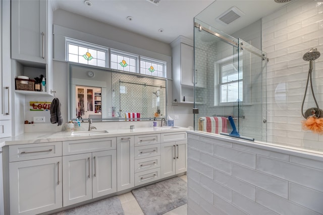 bathroom with double vanity, a sink, visible vents, and a shower stall