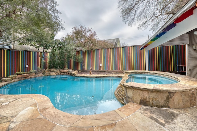 view of swimming pool with a fenced backyard and a pool with connected hot tub