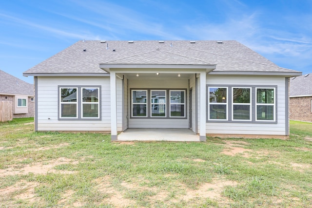 back of property featuring a patio area, a shingled roof, and a lawn