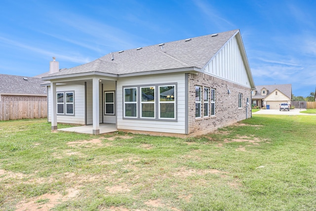 rear view of house with a yard, a patio area, fence, and brick siding