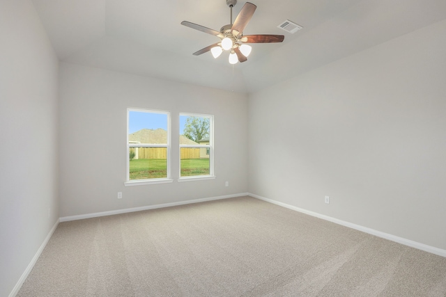 carpeted spare room with a ceiling fan, visible vents, and baseboards