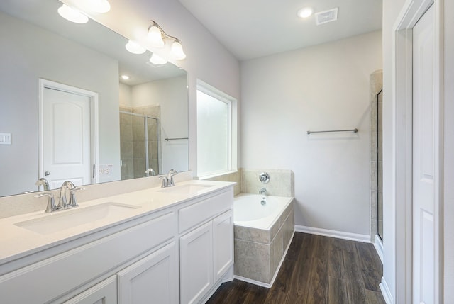 bathroom with wood finished floors, a stall shower, a sink, and visible vents