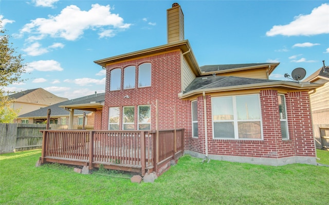 rear view of house featuring a deck, brick siding, a lawn, and a chimney