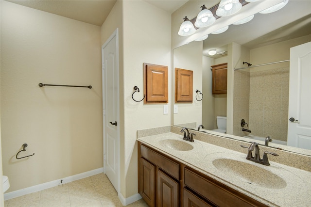 bathroom featuring toilet, double vanity, baseboards, and a sink