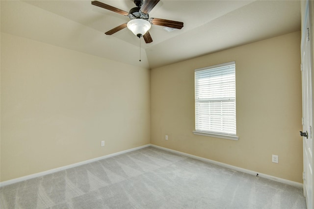 empty room featuring light carpet, vaulted ceiling, a ceiling fan, and baseboards