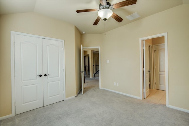 unfurnished bedroom featuring light carpet, vaulted ceiling, a closet, and visible vents