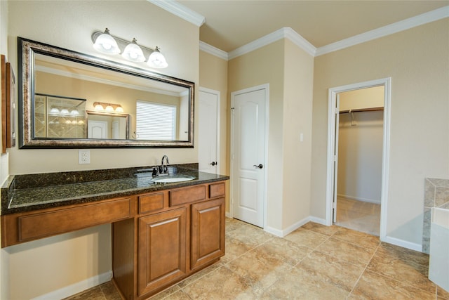 bathroom featuring ornamental molding, baseboards, a spacious closet, and vanity