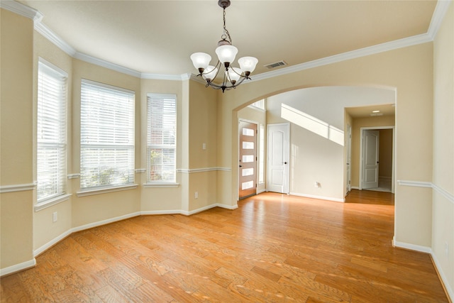 unfurnished room featuring light wood finished floors, a notable chandelier, arched walkways, and crown molding