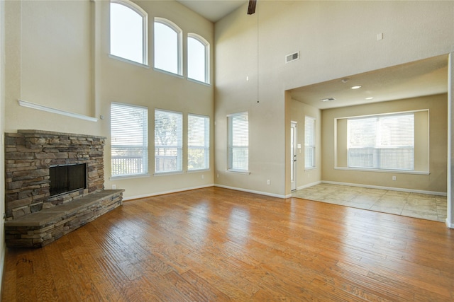 unfurnished living room featuring light wood-type flooring, a wealth of natural light, a fireplace, and visible vents