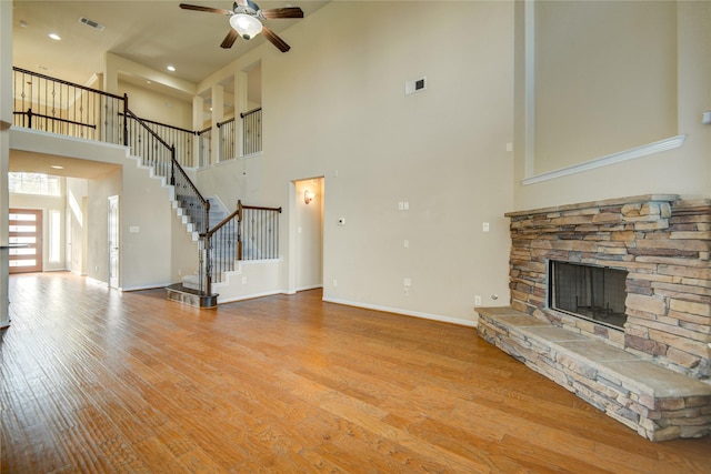 unfurnished living room with a fireplace, visible vents, stairway, light wood-style floors, and baseboards