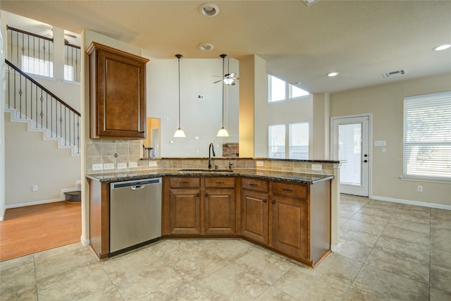 kitchen with a sink, dark stone counters, brown cabinetry, and stainless steel dishwasher