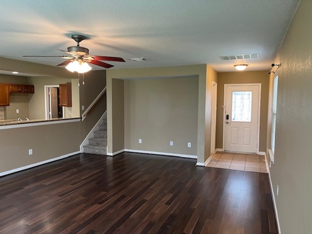 foyer entrance with dark wood-type flooring, visible vents, stairway, and baseboards