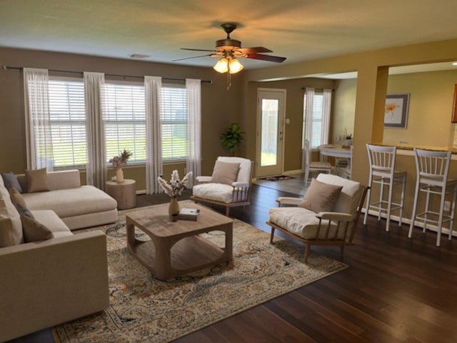 living room featuring dark wood-style flooring, ceiling fan, and baseboards