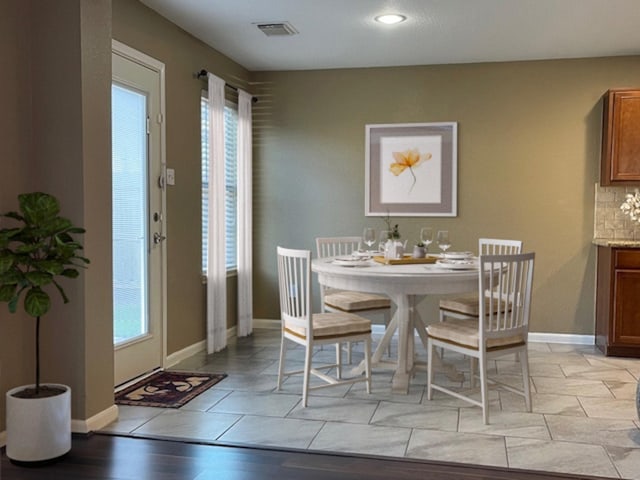 dining room featuring light tile patterned floors, plenty of natural light, visible vents, and baseboards