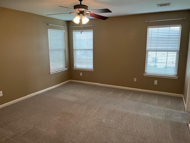 unfurnished room with ceiling fan, carpet flooring, visible vents, and baseboards