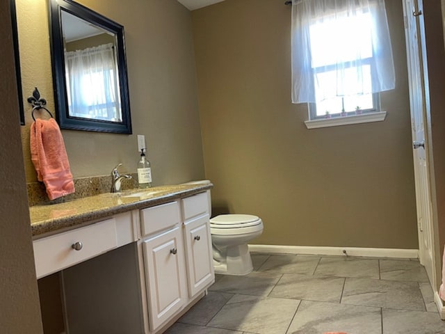 full bath featuring baseboards, vanity, and toilet