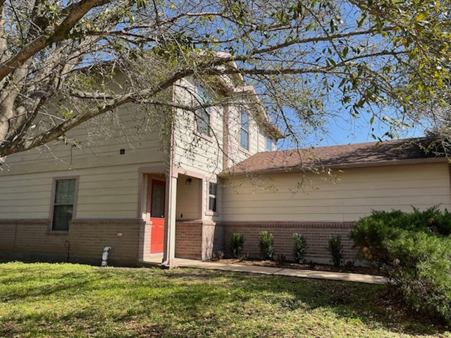 view of front of home featuring brick siding and a front lawn