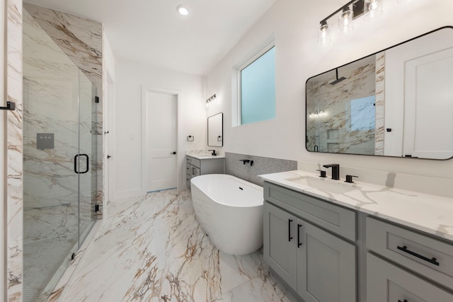 full bathroom with a marble finish shower, a sink, marble finish floor, a freestanding bath, and two vanities