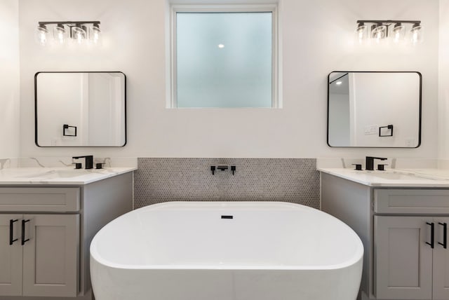 bathroom featuring a freestanding bath, two vanities, and a sink