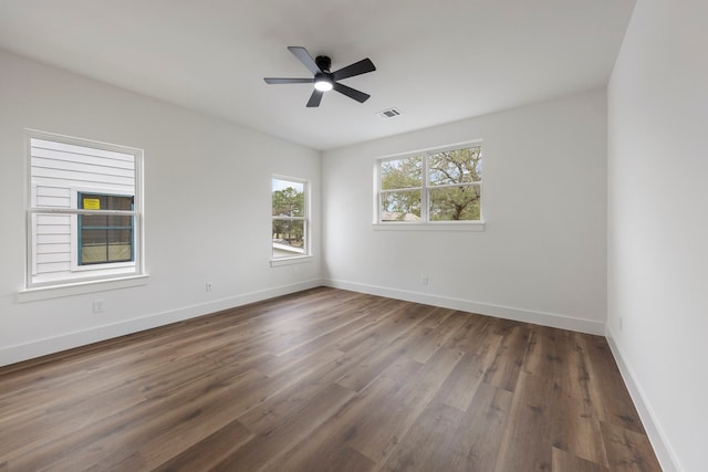 spare room with baseboards, visible vents, ceiling fan, and dark wood-type flooring