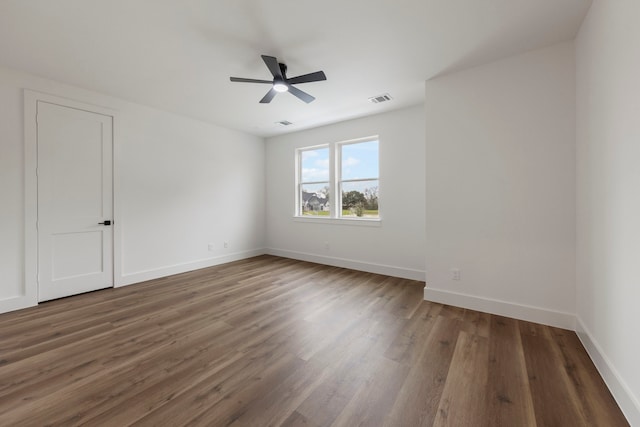 empty room with ceiling fan, wood finished floors, visible vents, and baseboards