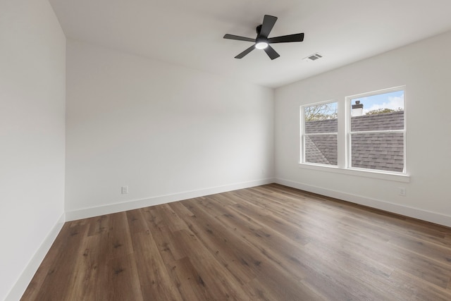 spare room featuring a ceiling fan, baseboards, visible vents, and wood finished floors