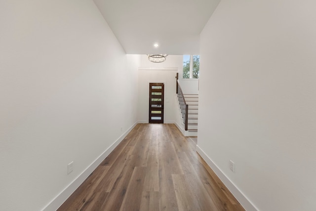 hallway featuring baseboards, stairway, and wood finished floors