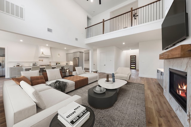 living area with a glass covered fireplace, visible vents, recessed lighting, and wood finished floors