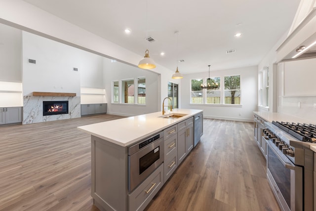 kitchen featuring gray cabinetry, a sink, open floor plan, light countertops, and decorative light fixtures