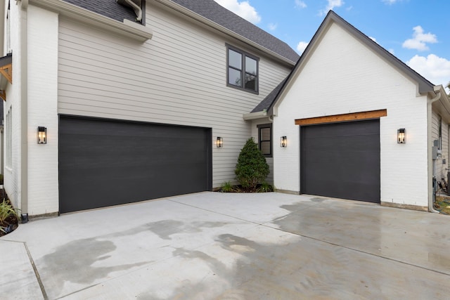 view of front of property featuring a shingled roof, brick siding, and driveway