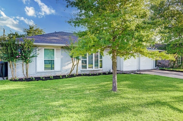 view of front facade with an attached garage, driveway, a front yard, and brick siding