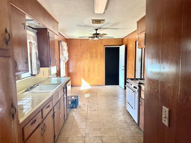 kitchen featuring visible vents, tile counters, dishwashing machine, gas range gas stove, and a sink