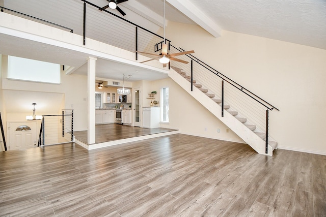 unfurnished living room with beamed ceiling, wood finished floors, a ceiling fan, and baseboards