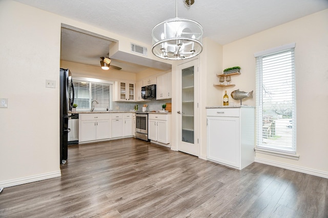 653 Davis Rd, League City, TX 77573 - kitchen with dark wood finished floors, white cabinetry, black appliances, a sink, and plenty of natural light