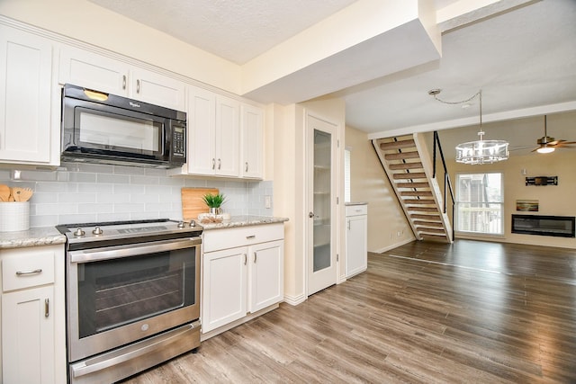 653 Davis Rd, League City, TX 77573 - kitchen with white cabinets, light wood-style floors, black microwave, backsplash, and electric range