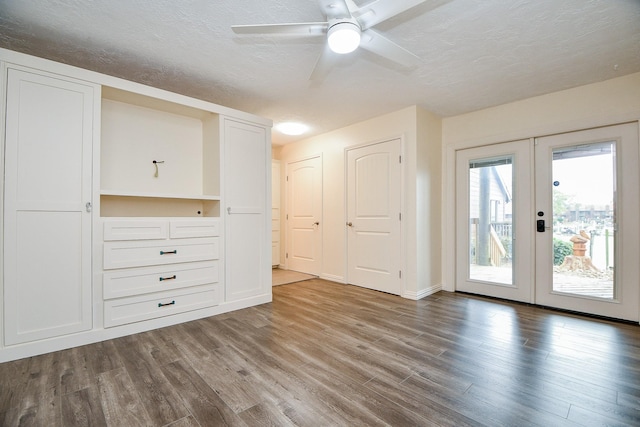 empty room featuring french doors, ceiling fan, a textured ceiling, wood finished floors, and baseboards