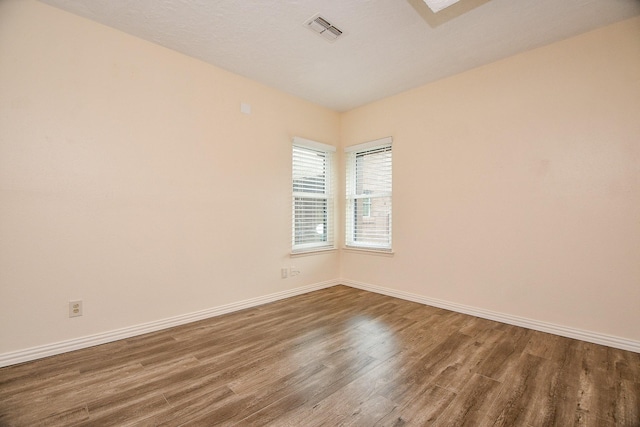 unfurnished room with baseboards, visible vents, and wood finished floors