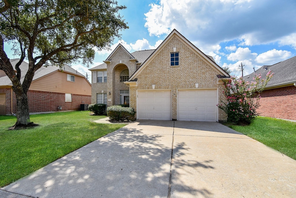 traditional-style house featuring cooling unit, a front lawn, concrete driveway, and brick siding