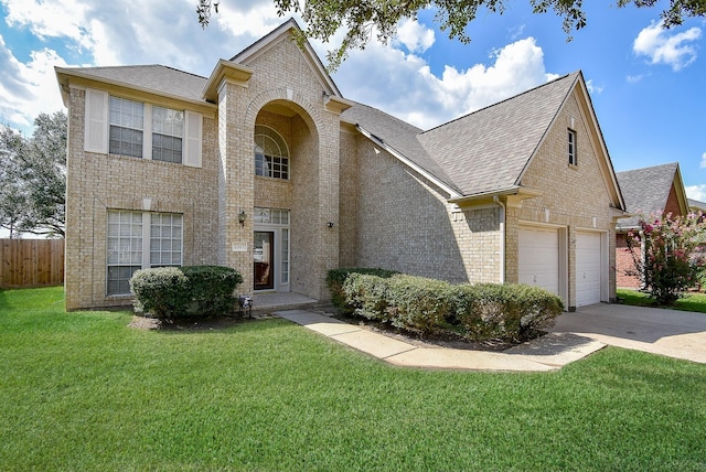 traditional-style house with driveway, brick siding, a front lawn, and fence