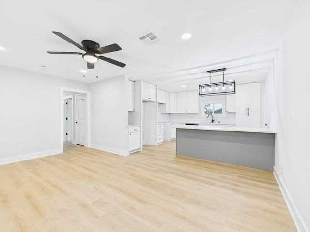 kitchen featuring a peninsula, light wood-style floors, visible vents, and white cabinets