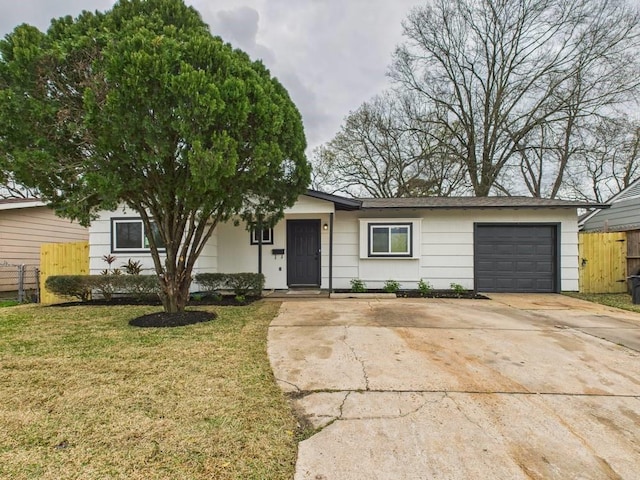 ranch-style house featuring a front lawn, concrete driveway, fence, and an attached garage