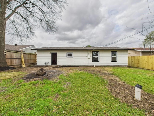 rear view of house with a fenced backyard and a yard